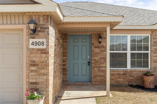 entrance to property featuring brick siding and roof with shingles