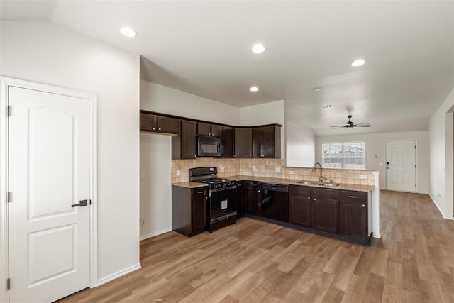 kitchen with a peninsula, a sink, decorative backsplash, black appliances, and dark brown cabinetry