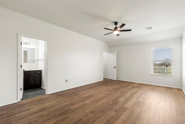 unfurnished bedroom featuring vaulted ceiling, visible vents, baseboards, and wood finished floors