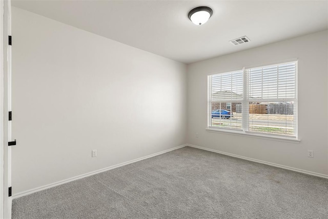 empty room with carpet, visible vents, and baseboards