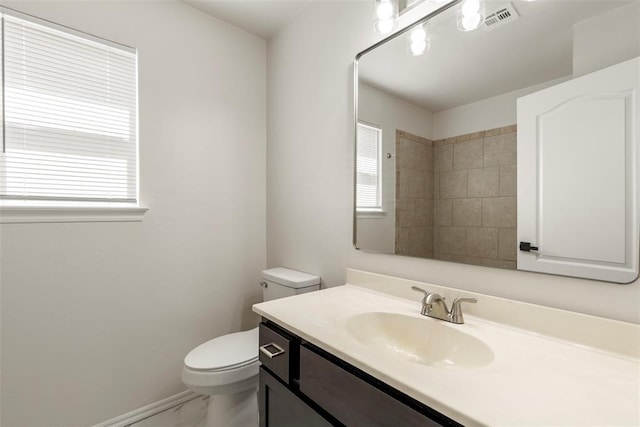 bathroom with vanity, toilet, baseboards, and visible vents