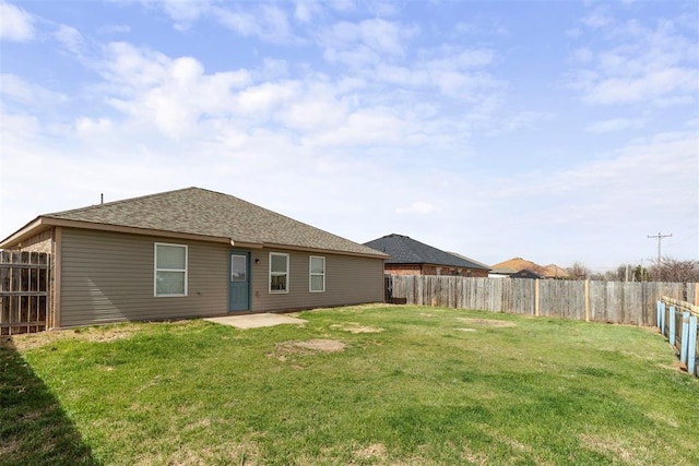 back of property featuring a fenced backyard, a yard, and roof with shingles