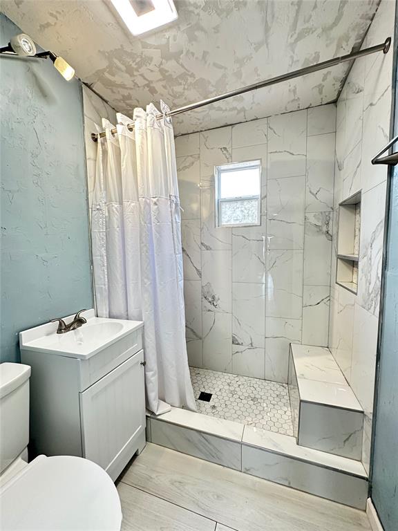 full bathroom with toilet, a stall shower, and vanity