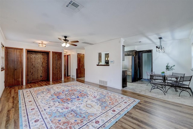 interior space featuring visible vents, a ceiling fan, and wood finished floors