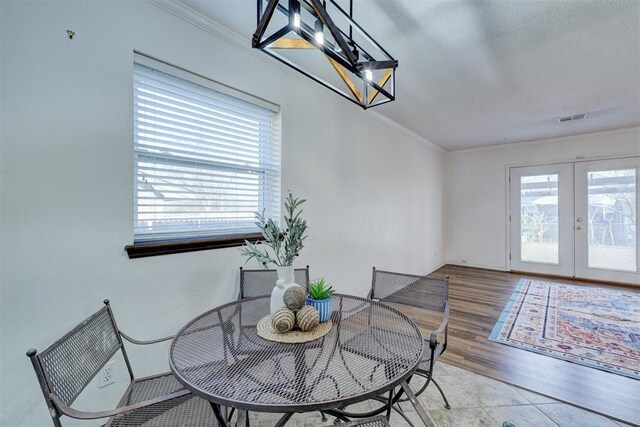 dining room featuring visible vents, wood finished floors, french doors, crown molding, and a chandelier