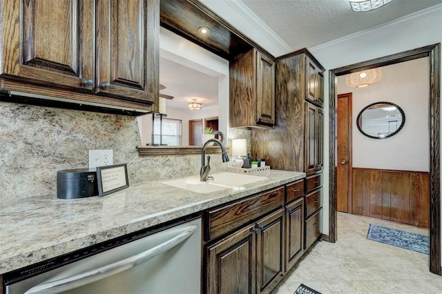 kitchen featuring dark brown cabinetry, ornamental molding, wainscoting, stainless steel dishwasher, and a sink