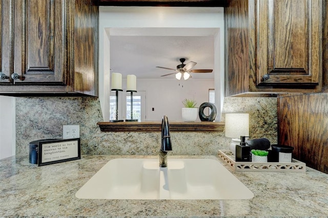 kitchen with ceiling fan, dark brown cabinets, backsplash, and a sink