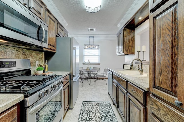 kitchen with crown molding, visible vents, appliances with stainless steel finishes, and a sink