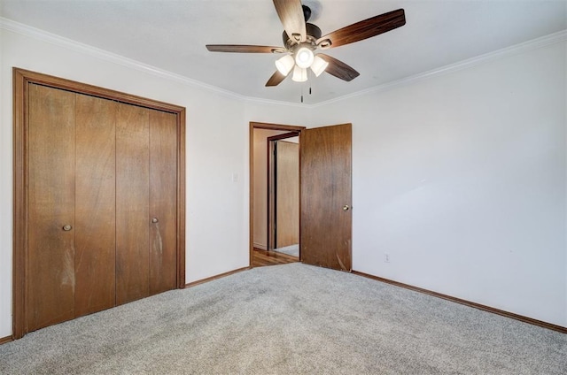 unfurnished bedroom with a ceiling fan, a closet, carpet flooring, crown molding, and baseboards