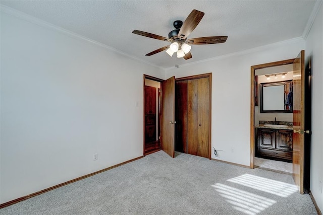 unfurnished bedroom featuring carpet flooring, crown molding, baseboards, and a sink