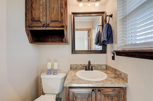 half bath featuring a healthy amount of sunlight, toilet, and vanity