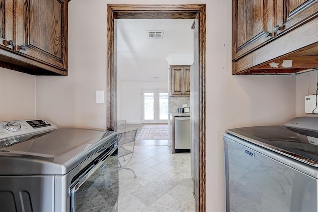 clothes washing area featuring independent washer and dryer, cabinet space, and visible vents