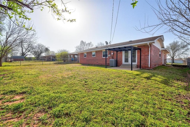 rear view of house featuring brick siding, a lawn, cooling unit, and a patio