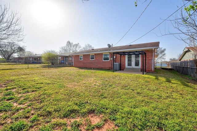 rear view of property with a lawn, a fenced backyard, cooling unit, french doors, and a patio area