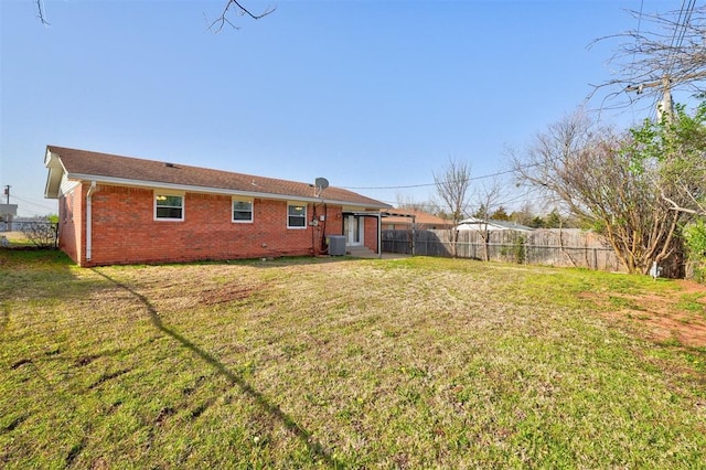 back of house featuring a yard, brick siding, cooling unit, and fence