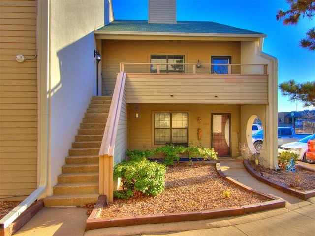 exterior space featuring a balcony, a chimney, and stairs