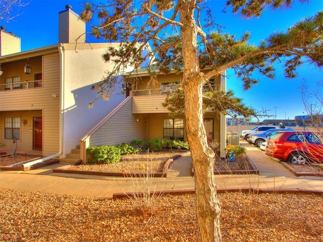 view of front of home featuring stucco siding, a balcony, and a chimney