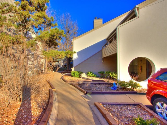 view of side of home with stucco siding and a chimney