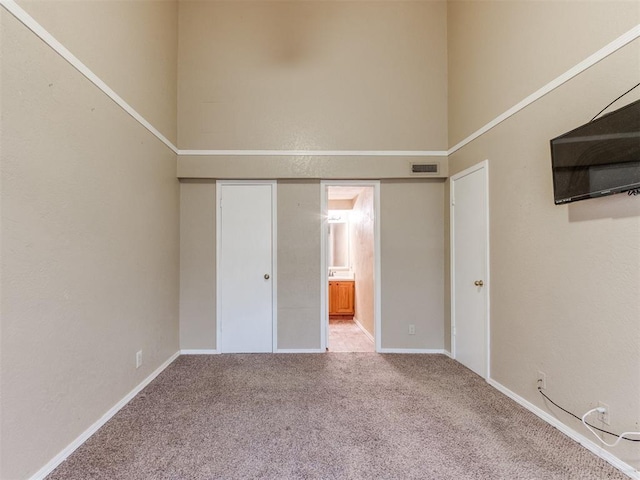 empty room featuring visible vents, carpet, and a high ceiling