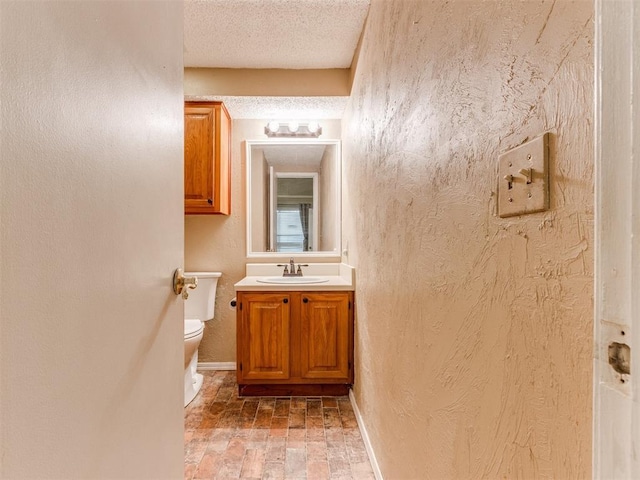 bathroom with a textured ceiling, toilet, baseboards, and a textured wall