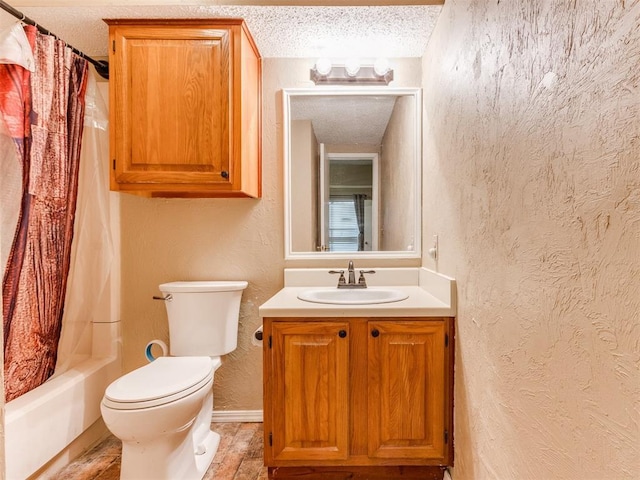 bathroom featuring toilet, vanity, shower / tub combo, a textured wall, and a textured ceiling