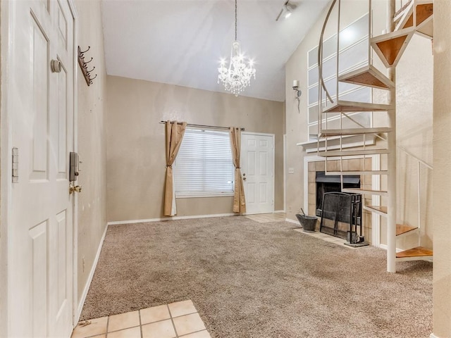 unfurnished living room with a notable chandelier, a tile fireplace, baseboards, and carpet