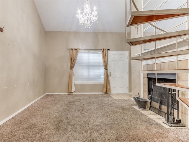 unfurnished living room with a notable chandelier, a tile fireplace, baseboards, and carpet