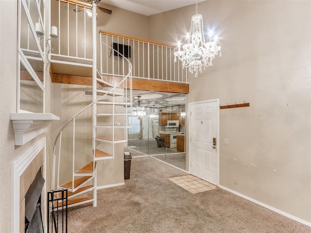 foyer entrance with baseboards, carpet floors, a high ceiling, a fireplace, and a chandelier