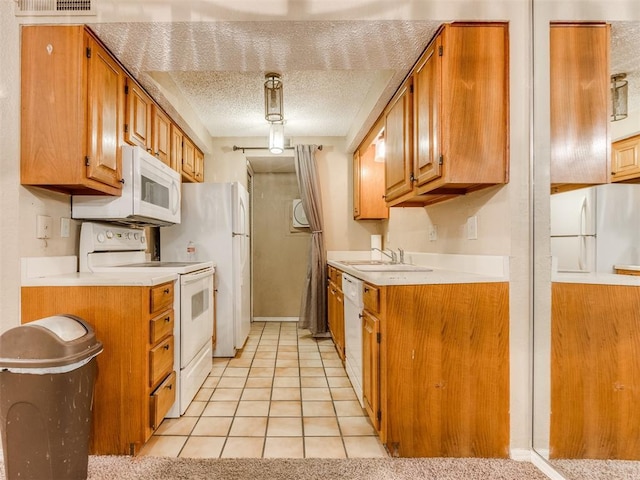 kitchen featuring a textured ceiling, white appliances, light countertops, and a sink