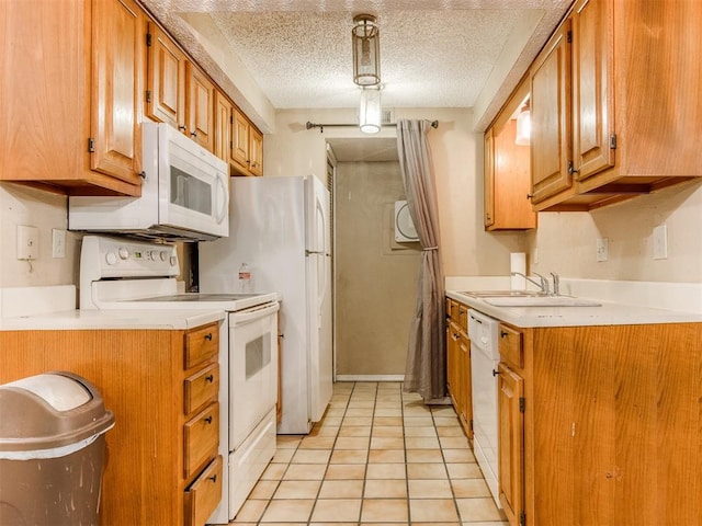 kitchen featuring white appliances, brown cabinetry, a sink, light countertops, and a textured ceiling