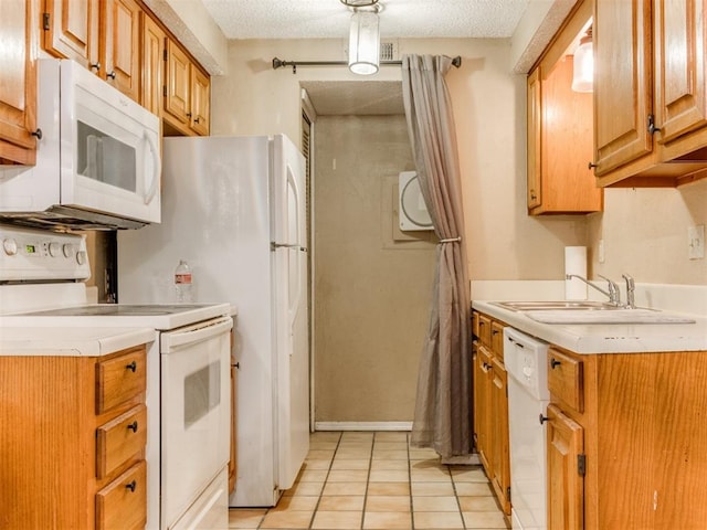 kitchen featuring a sink, white appliances, light countertops, and a textured ceiling