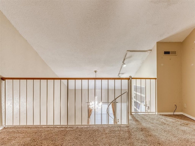 corridor with visible vents, a textured ceiling, track lighting, and carpet