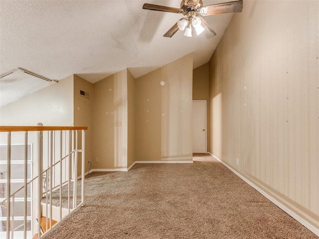 carpeted empty room featuring visible vents, baseboards, vaulted ceiling, a textured ceiling, and a ceiling fan