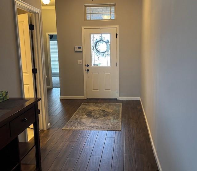 foyer with dark wood-type flooring and baseboards