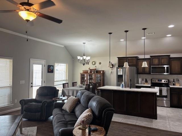 living room with visible vents, crown molding, lofted ceiling, ceiling fan with notable chandelier, and light tile patterned floors