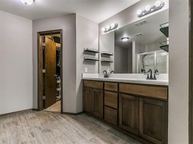 bathroom with a stall shower, visible vents, wood finished floors, and double vanity