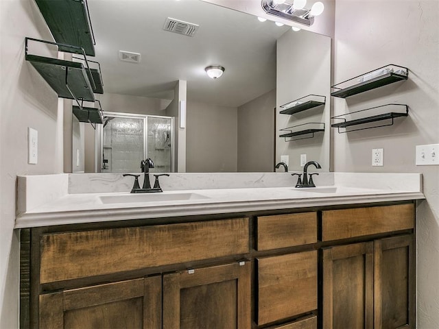 bathroom featuring double vanity, visible vents, a stall shower, and a sink