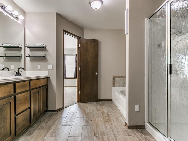 full bathroom with a garden tub, a stall shower, wood finished floors, baseboards, and vanity