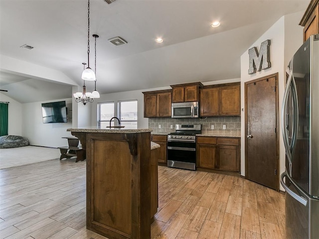 kitchen featuring visible vents, lofted ceiling, a sink, stainless steel appliances, and open floor plan