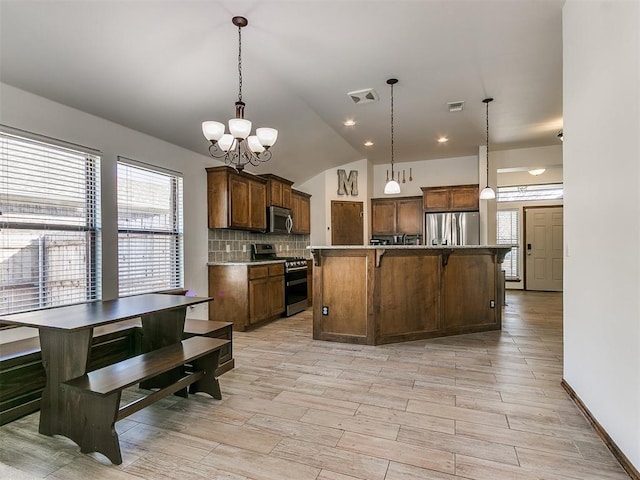 kitchen with visible vents, vaulted ceiling, decorative backsplash, appliances with stainless steel finishes, and an inviting chandelier