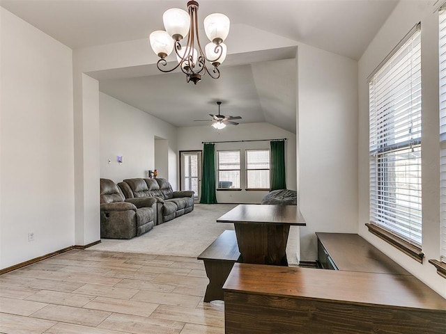 living area featuring light wood finished floors, ceiling fan with notable chandelier, baseboards, and lofted ceiling