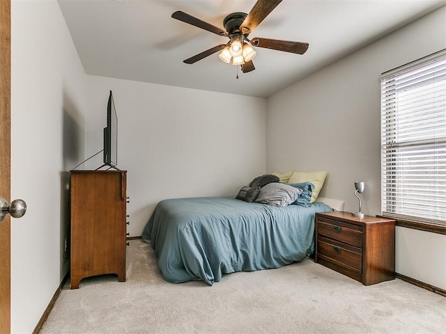 bedroom featuring baseboards, light colored carpet, and a ceiling fan