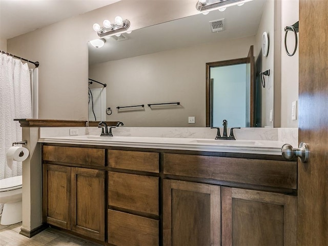 bathroom featuring double vanity, visible vents, toilet, and a sink