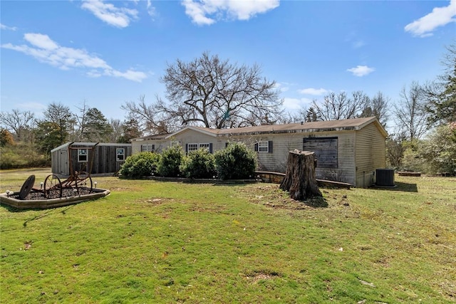 rear view of property featuring a storage shed, an outdoor structure, a lawn, and central AC