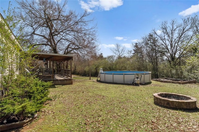 view of yard with an outdoor pool, a deck, and an outdoor fire pit