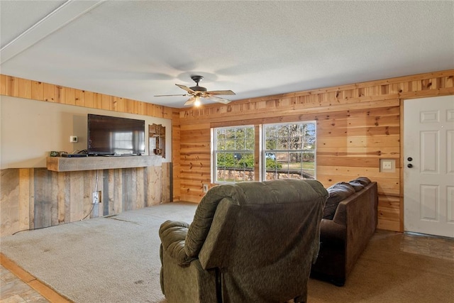living room featuring carpet flooring, wood walls, a textured ceiling, and a ceiling fan