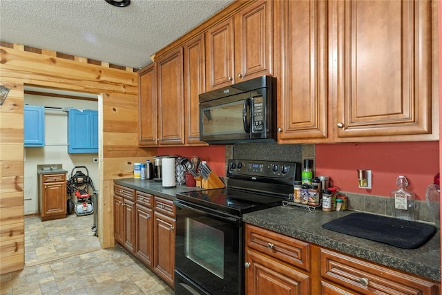 kitchen with dark countertops, black appliances, brown cabinets, stone finish floor, and a textured ceiling