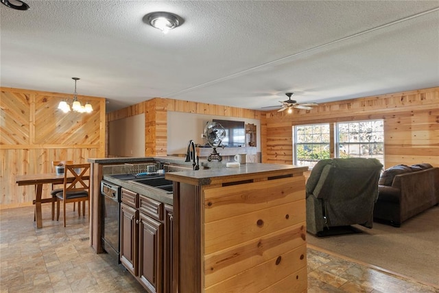 kitchen featuring a sink, open floor plan, dishwasher, and wood walls