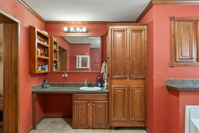 bathroom with vanity, baseboards, a textured ceiling, crown molding, and tile patterned floors