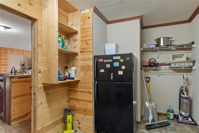 kitchen with crown molding, wood walls, freestanding refrigerator, and a textured ceiling